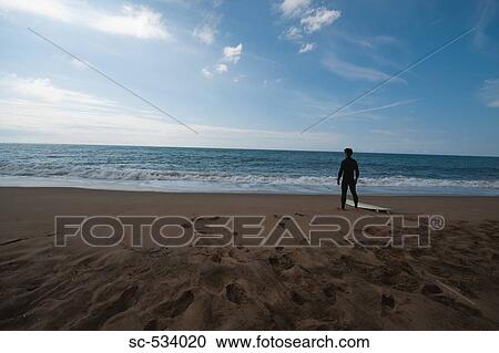 Young man in wetsuit standing on beach View Large Photo Image Stock Image - Young man in wetsuit standing on beach . Fotosearch
