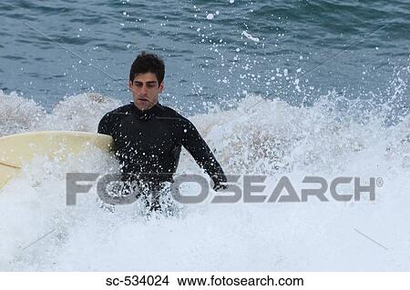 Young man inside the sea with his surfboard View Large Photo Image Picture - Young man inside the sea with his surfboard. Fotosearch