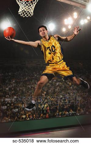 Stock Photo - Young man jumping and holding basketball . Fotosearch