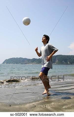 Stock Image - Young Man Playing Soccer On A Beach. Fotosearch
