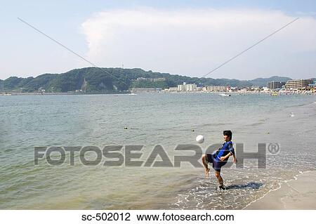 Stock Image - Young Man Playing Soccer On A Beach. Fotosearch