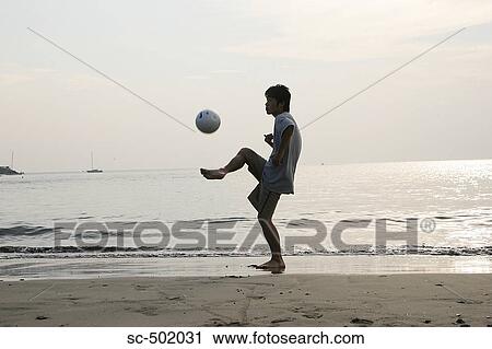 Stock Image - Young Man Playing Soccer On A Beach. Fotosearch