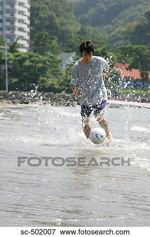 Stock Photo - Young Man Playing Soccer On A Beach. Fotosearch