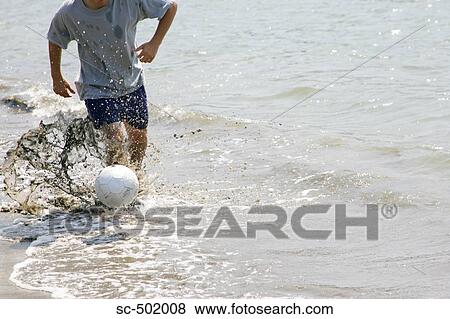 Stock Photo - Young Man Playing Soccer On A Beach. Fotosearch