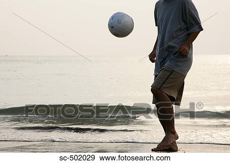 Stock Photo - Young Man Playing Soccer On A Beach. Fotosearch