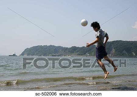 Stock Photograph - Young Man Playing Soccer On A Beach. Fotosearch