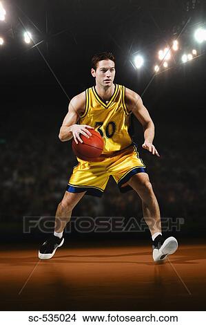 Picture - Young man playing with basketball. Fotosearch