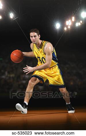Stock Image - Young man playing with basketball. Fotosearch