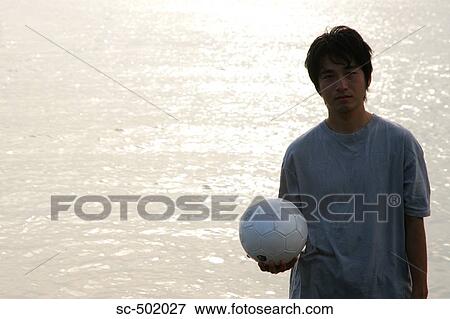 Stock Photo - Young Man Posing With A Soccer Ball on the Beach. Fotosearch