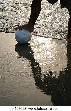 Stock Photo - Young Man Posing With A Soccer Ball on the Beach. Fotosearch