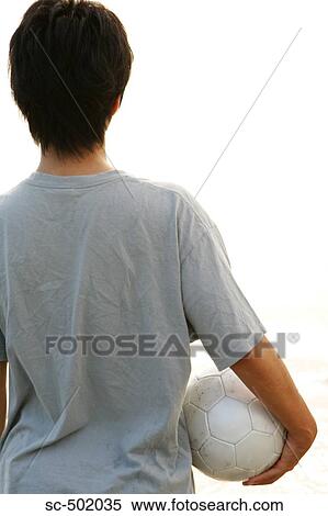 Stock Photography - Young Man Posing With A Soccer Ball on the Beach. Fotosearch