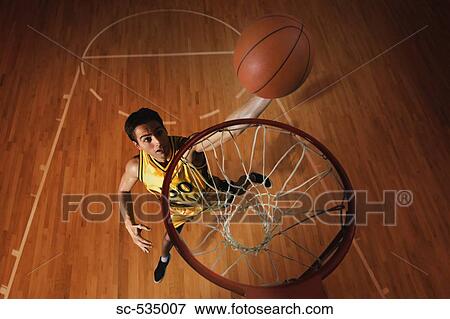 Young man throwing basketball in hoop View Large Photo Image Stock Photo - Young man throwing basketball in hoop. Fotosearch