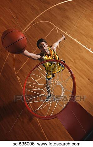 Stock Photograph - Young man throwing basketball in hoop. Fotosearch