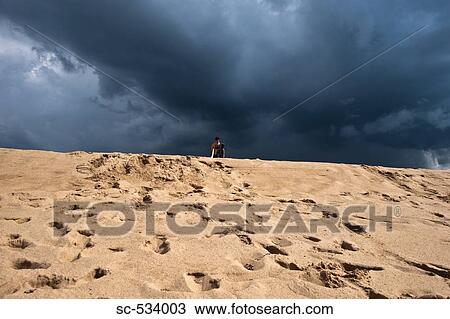 Young man walking on sand with surfboard View Large Photo Image Stock Image - Young man walking on sand with surfboard. Fotosearch