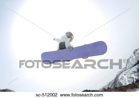 Stock Image - Young snowboarder mid air. Fotosearch