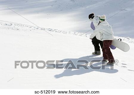 Stock Photo - Young snowboarders walking in snow. Fotosearch