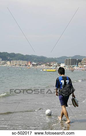Stock Photo - Young Soccer Player Walking On The Beach. Fotosearch