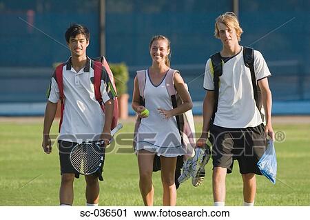 Stock Image - Young tennis players walking with equipment. Fotosearch