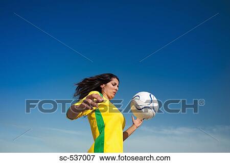 Stock Photo - Young woman playing with soccer ball. Fotosearch