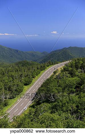Stock Image - Road through the countryside, Hokkaido. Fotosearch