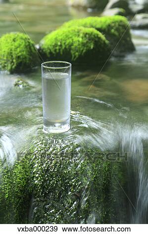 Glass of water near a mountain stream View Large Photo Image Stock Photo - Glass of water near a mountain stream. Fotosearch