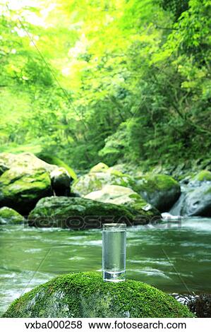 Glass of water near a mountain stream View Large Photo Image Stock Photo - Glass of water near a mountain stream. Fotosearch