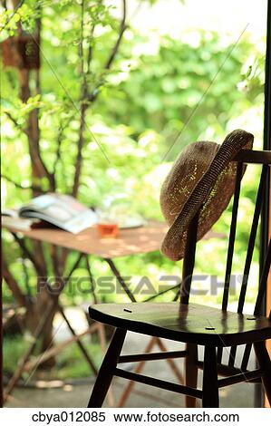 Hat on a chair near a garden View Large Photo Image Stock Photography - Hat on a chair near a garden. Fotosearch