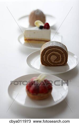 Stock Image - Mixed cakes in a row on a table. Fotosearch