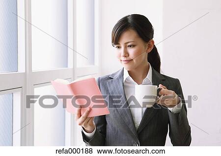 Businesswoman with agenda and coffee by the window View Large Photo Image Stock Photo - Businesswoman with agenda and coffee by the window. Fotosearch