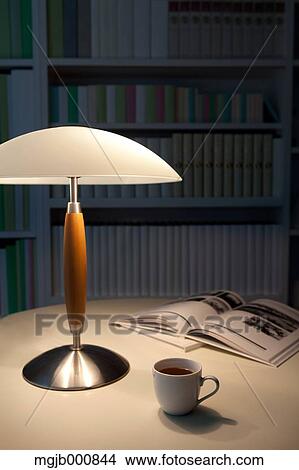 Picture - Coffee cup, lamp and books on a table. Fotosearch