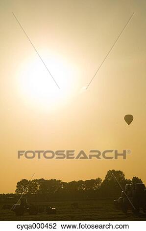 Stock Image - Countryside and balloon flying at sunset, Netherlands. Fotosearch
