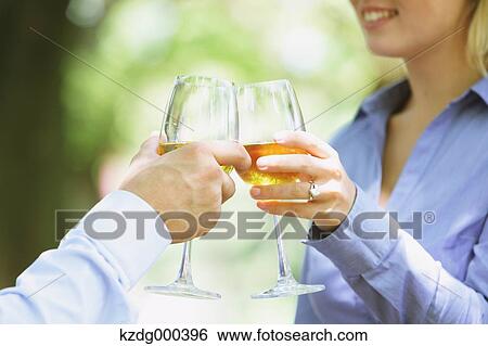 Stock Photograph - Couple cheering with white wine. Fotosearch