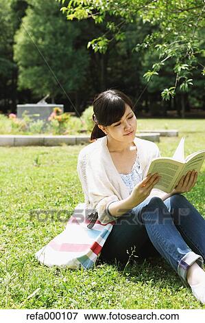 Female college student reading a book on grassland View Large Photo Image Stock Photo - Female college student reading a book on grassland. Fotosearch