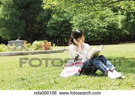 Female college student reading a book on grassland View Large Photo Image Stock Photograph - Female college student reading a book on grassland. Fotosearch