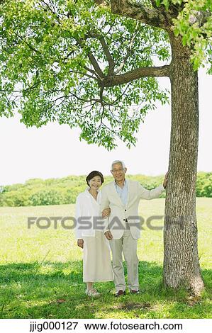 Senior couple by a tree smiling at camera View Large Photo Image Stock Photo - Senior couple by a tree smiling at camera. Fotosearch