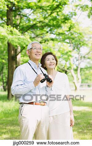 Stock Photo - Senior couple with binoculars looking away. Fotosearch