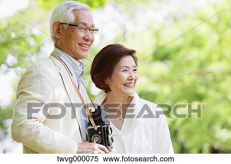 Stock Photography - Senior couple with vintage camera smiling away. Fotosearch