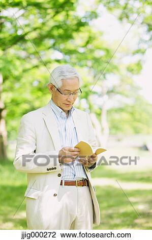 Senior man reading a book on grassland View Large Photo Image Stock Image - Senior man reading a book on grassland. Fotosearch
