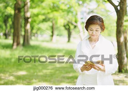 Senior woman reading a book on grassland View Large Photo Image Stock Photograph - Senior woman reading a book on grassland. Fotosearch
