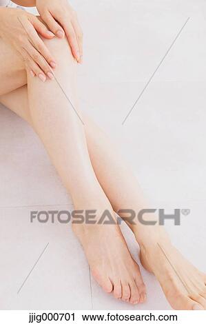 Woman massaging her legs on the floor View Large Photo Image Stock Image - Woman massaging her legs on the floor. Fotosearch