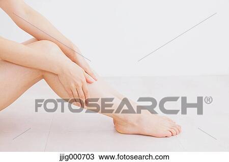Woman massaging her legs on the floor View Large Photo Image Stock Image - Woman massaging her legs on the floor. Fotosearch