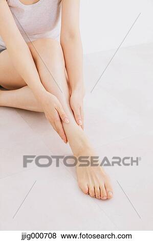 Woman massaging her legs on the floor View Large Photo Image Stock Photo - Woman massaging her legs on the floor. Fotosearch