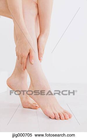 Woman massaging her legs on the floor View Large Photo Image Stock Photography - Woman massaging her legs on the floor. Fotosearch