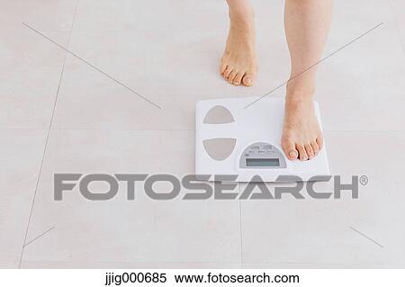 Stock Photography - Woman riding on weight scale. Fotosearch