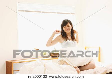 Woman sitting on bed stretching arms View Large Photo Image Stock Image - Woman sitting on bed stretching arms. Fotosearch
