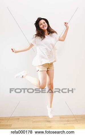 Young woman in a white shirt jumping View Large Photo Image Stock Photo - Young woman in a white shirt jumping. Fotosearch