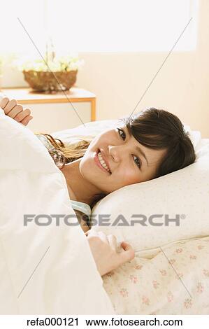 Young woman in bed smiling at camera View Large Photo Image Stock Image - Young woman in bed smiling at camera. Fotosearch