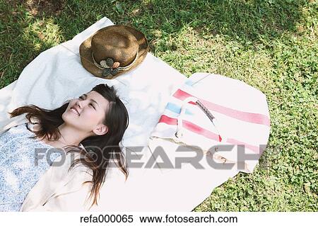 Stock Photography - Young woman laying on grassland smiling. Fotosearch