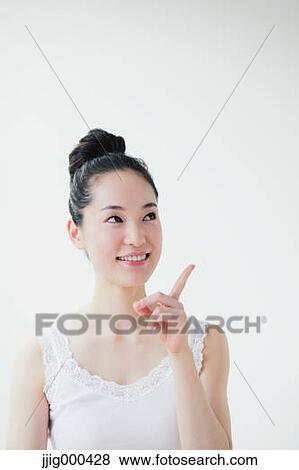 Stock Photo - Young woman pointing finger up smiling. Fotosearch