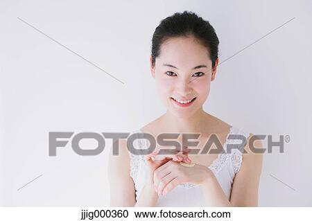 Stock Image - Young woman putting foundation cream. Fotosearch